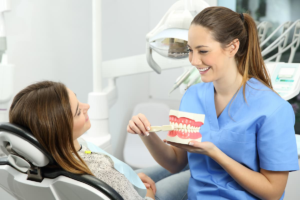 Female dental hygienist showing patient correct teeth brushing technique